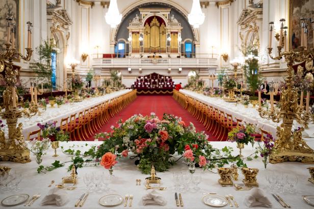 Ein festlich gedeckter Tisch in einem prunkvollen Saal mit langem Tisch und Blumenschmuck.