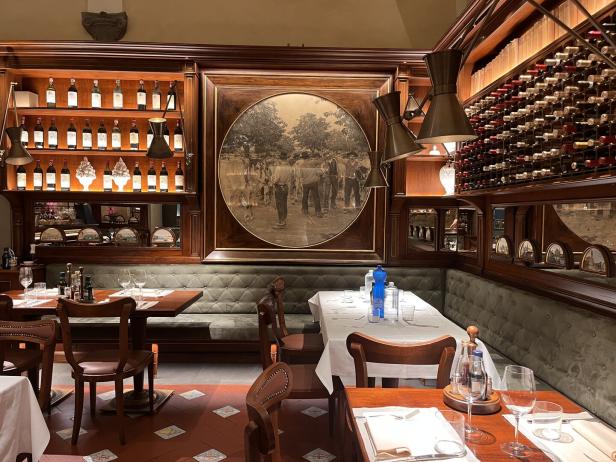 Ein elegant eingerichtetes Restaurant mit Tischen, Stühlen und Weinregalen.
