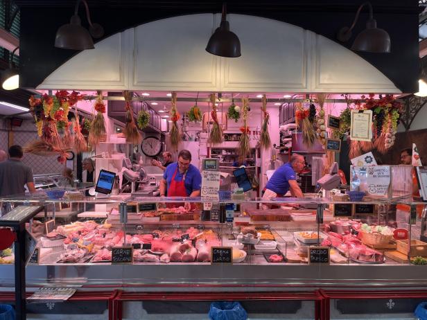 Ein belebter Fleischstand auf einem Markt mit einer großen Auswahl an Fleischprodukten.