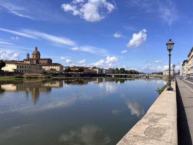 Blick über den Arno in Florenz auf Gebäude und eine Brücke.