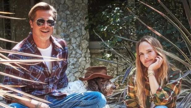 Brad Pitt und eine Frau sitzen mit einem Hund im Freien.
