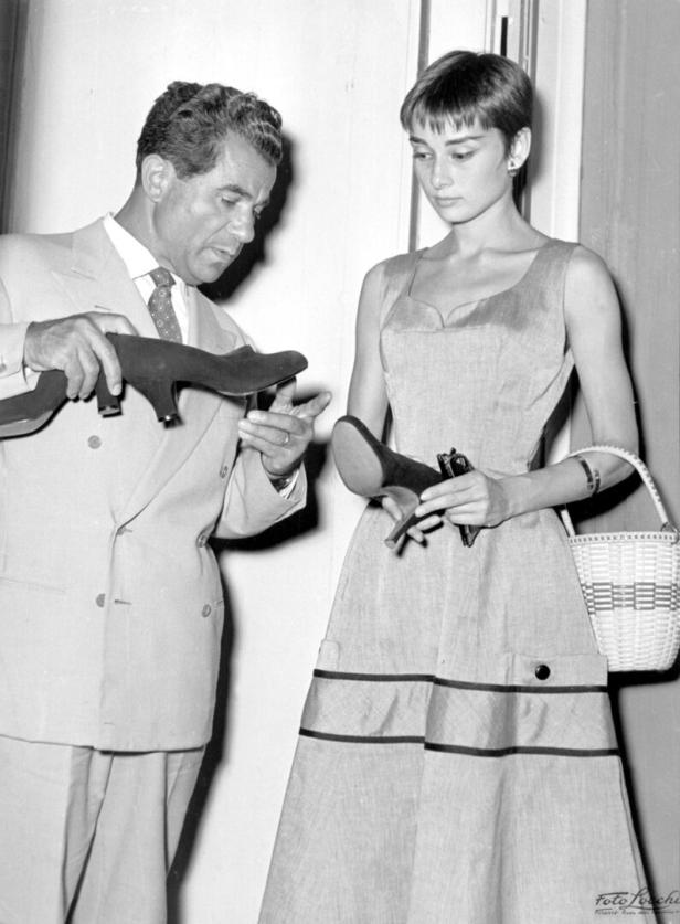 Audrey Hepburn betrachtet mit einem Mann ein Paar Schuhe.