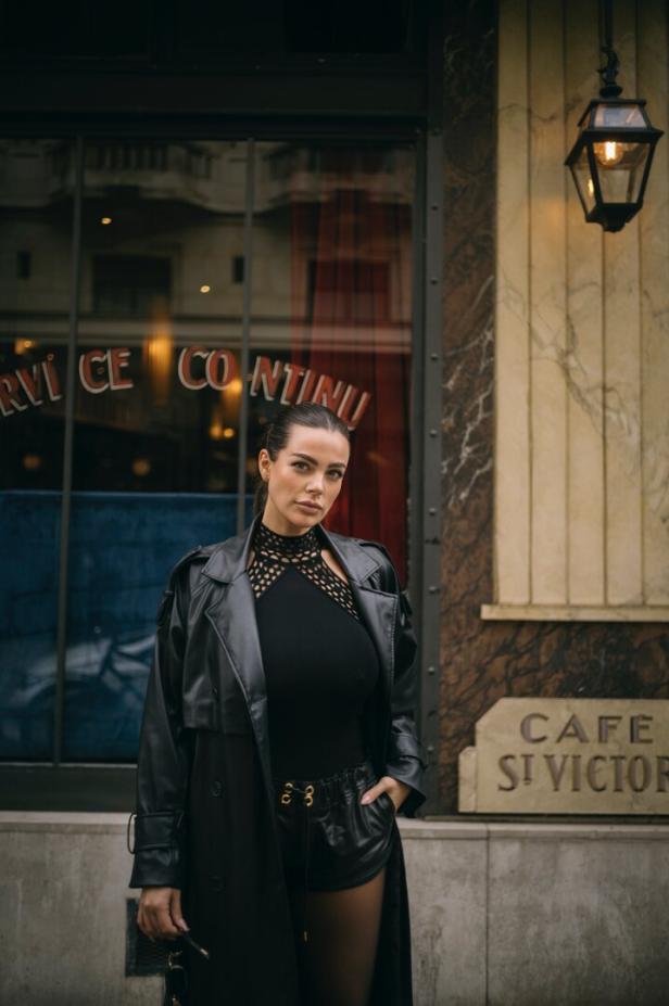 Eine Frau in einem schwarzen Outfit steht vor dem „Café St Victor“.