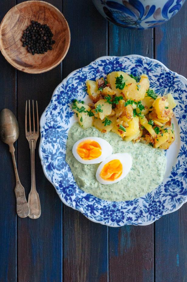 Ein Teller mit Bratkartoffeln, grüner Soße und zwei halbierten Eiern.