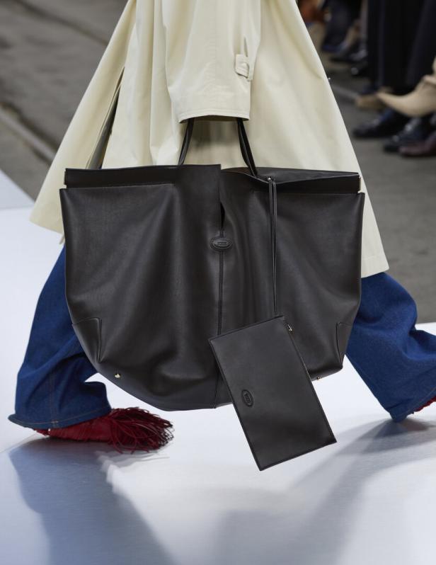 Eine große, schwarze Ledertasche von Tod's wird von einer Person auf dem Laufsteg getragen.