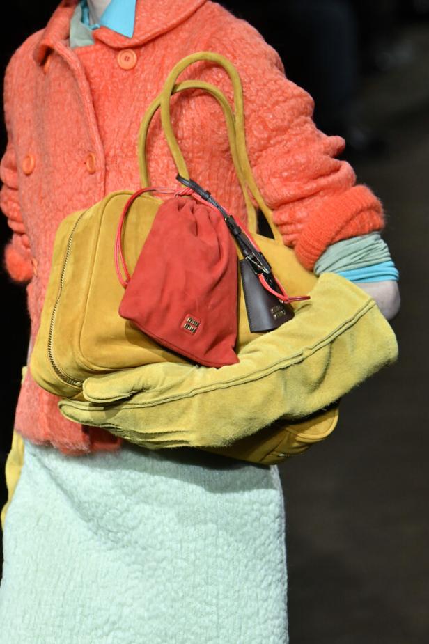 Eine Person trägt eine gelbe Tasche, einen roten Beutel und gelbe Handschuhe.