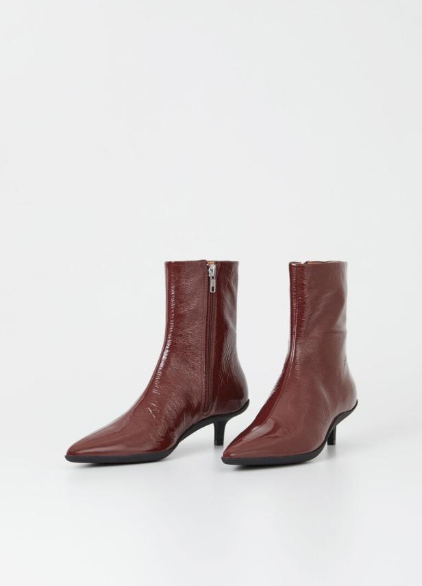Zwei glänzende, braune Stiefeletten mit Reißverschluss und kleinem Absatz stehen vor einem weißen Hintergrund.
