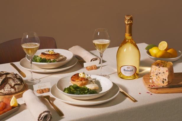 Eine gedeckte Tafel mit Essen, Champagner-Gläsern und einer Champagnerflasche.