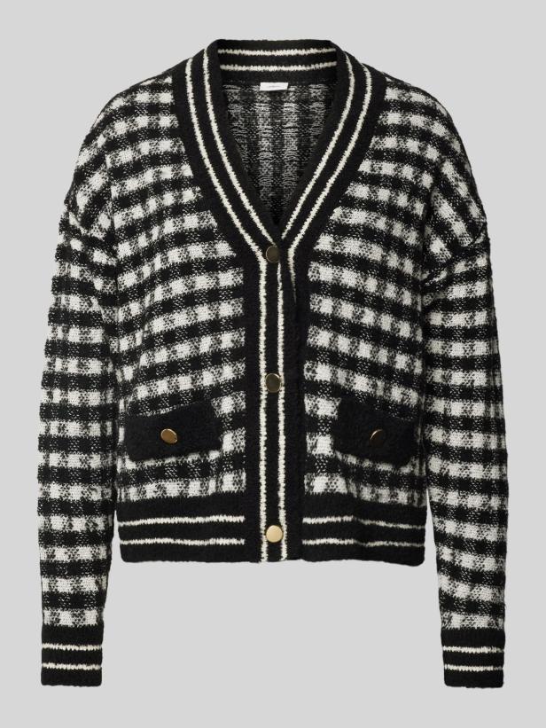 Eine schwarz-weiß karierte Strickjacke mit goldenen Knöpfen und Taschen.
