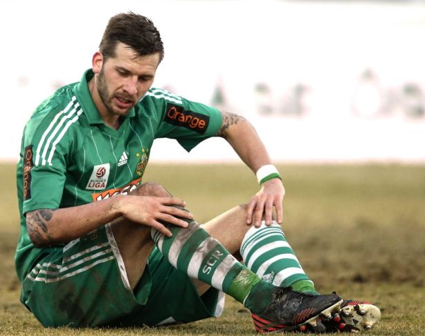 Ein Fußballspieler sitzt mit schmutziger Kleidung auf dem Feld.