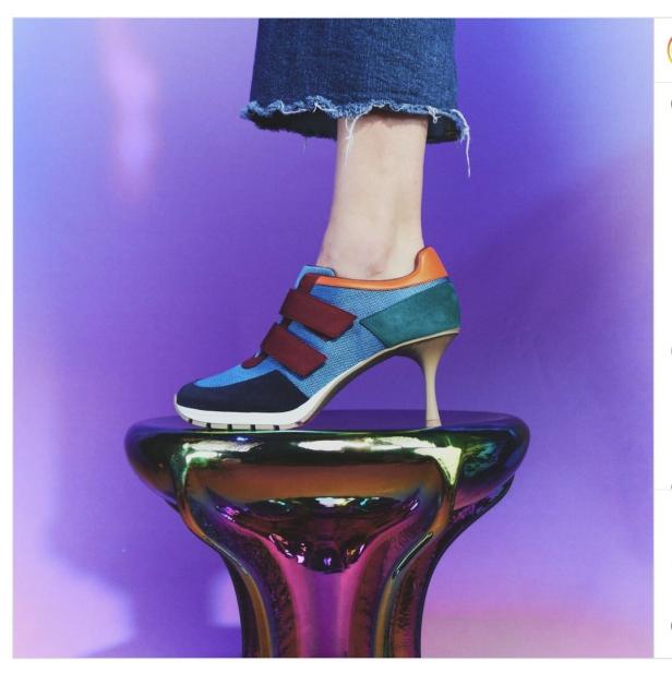 Ein Fuß in einem bunten High-Heel-Sneaker steht auf einem schimmernden Sockel.