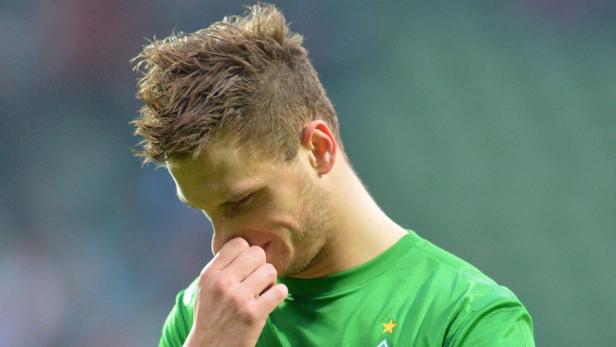 Ein Fußballspieler im grünen Trikot hält sich die Nase zu.