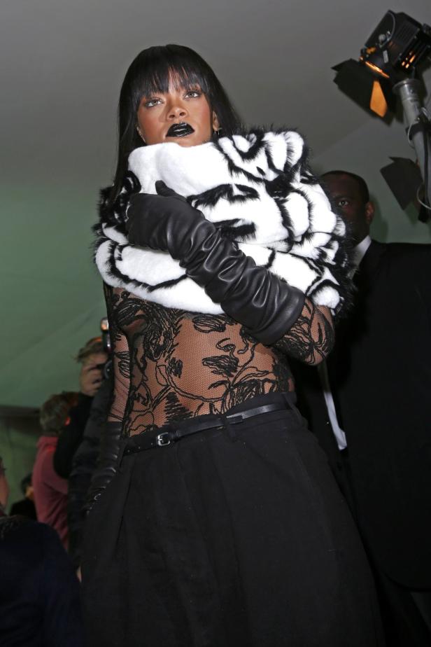Rihanna trägt einen schwarz-weißen Schal, schwarze Handschuhe und schwarzen Lippenstift.