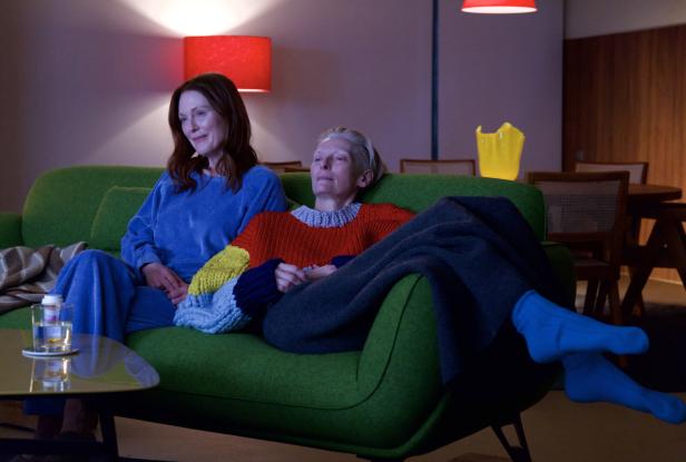 Julianne Moore und Tilda Swinton sitzen entspannt auf einem grünen Sofa.