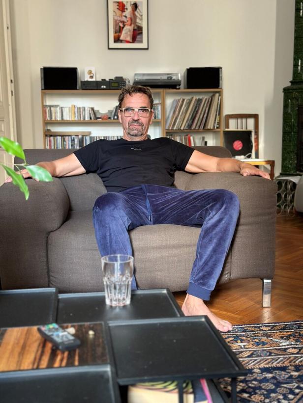 Ein Mann mit Brille sitzt entspannt in einem Sessel in seinem Wohnzimmer.
