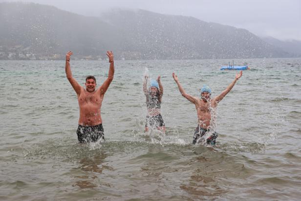 Drei Menschen planschen im Attersee im Winter