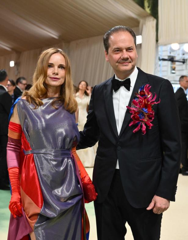 Eine Frau in einem farbenfrohen Kleid und ein Mann im Smoking posieren für ein Foto.