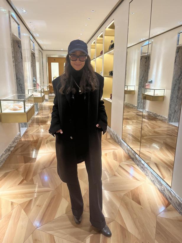 Eine Frau mit Sonnenbrille und Mütze steht in einem eleganten Geschäft.