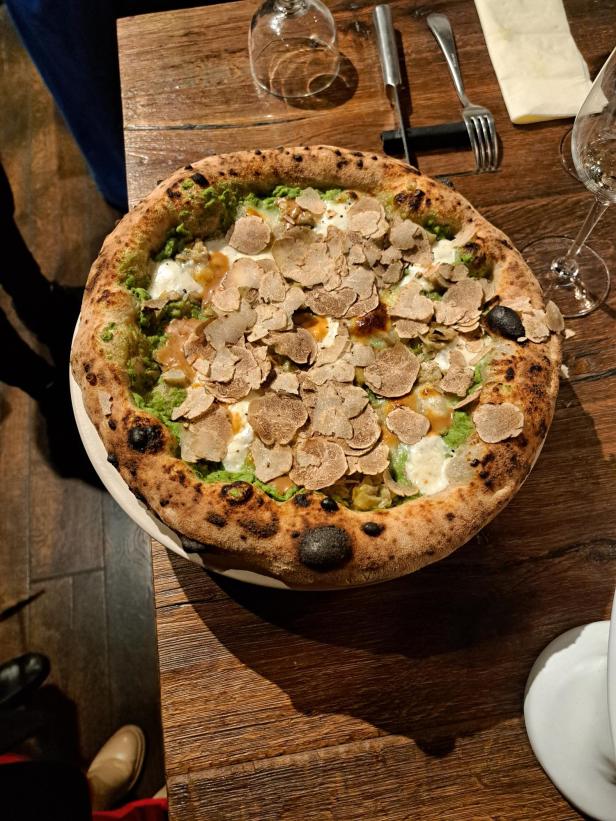 Eine Pizza „Terra Magnatum“ mit Trüffeln auf einem Holztisch.