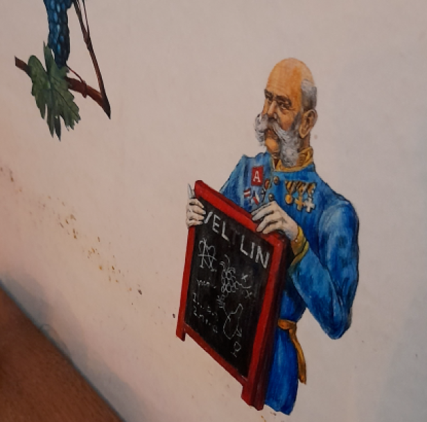 Kaiser Franz Joseph ist auf eine Wand gemalt - er hat eine Tafel in der Hand, auf der Veltlin steht.
