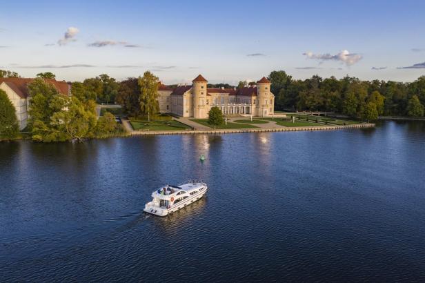 Ein Hausboot befindet sich auf einem See vor einem Schloss.