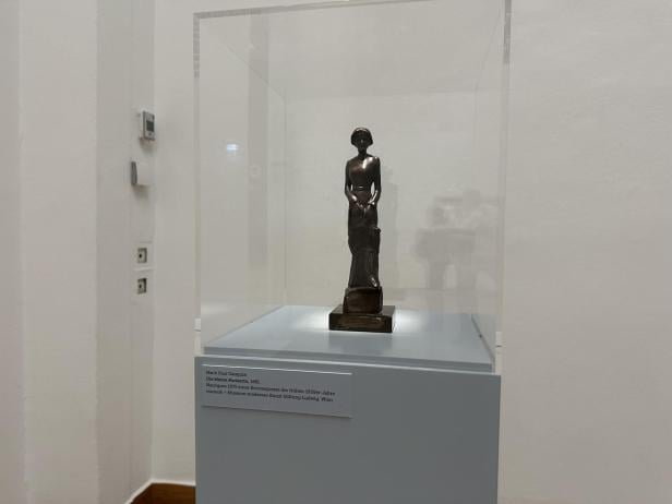 Eine kleine Bronze-Statue einer Frau in einer Vitrine