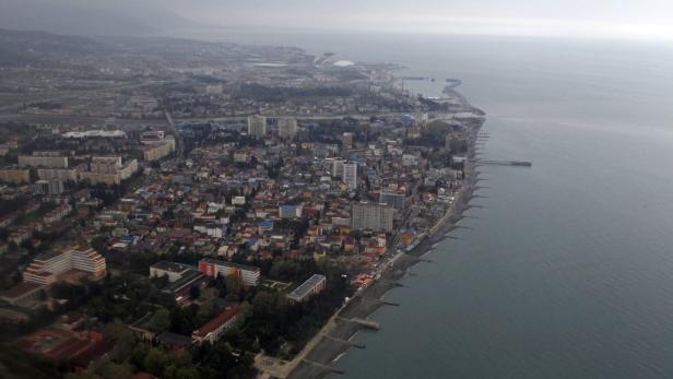 Luftaufnahme einer Küstenstadt mit Wohngebäuden und dem Meer.