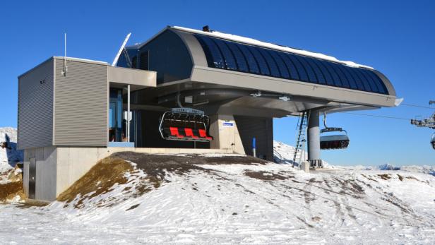 Eine moderne Liftstation mit Sesseln im Schnee unter blauem Himmel.