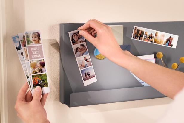 Auf einer Magnettafel hängt eine Person Fotostreifen hin.