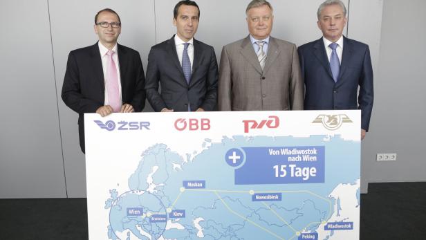 Vier Männer präsentieren eine Karte der Zugstrecke von Wladiwostok nach Wien in 15 Tagen.