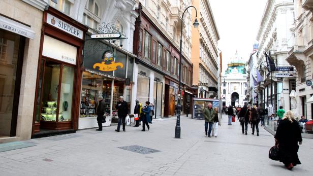 Die belebte Kärntner Straße in Wien mit Passanten und Geschäften wie Giorgio Armani und Chanel.