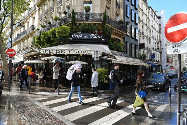 Menschen überqueren die Straße vor dem Café de Flore in Paris.