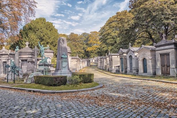 Ein Weg auf dem Friedhof Père Lachaise in Paris mit alten Gräbern und herbstlichem Laub.