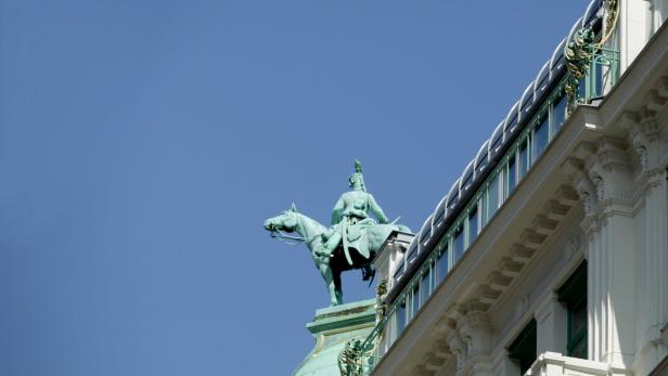 Eine Reiterstatue auf dem Dach eines Gebäudes unter blauem Himmel.