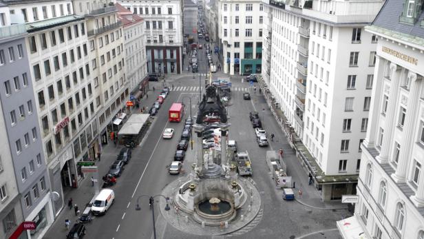 Blick auf den Donnerbrunnen in Wien, umgeben von Stadtverkehr und Gebäuden.