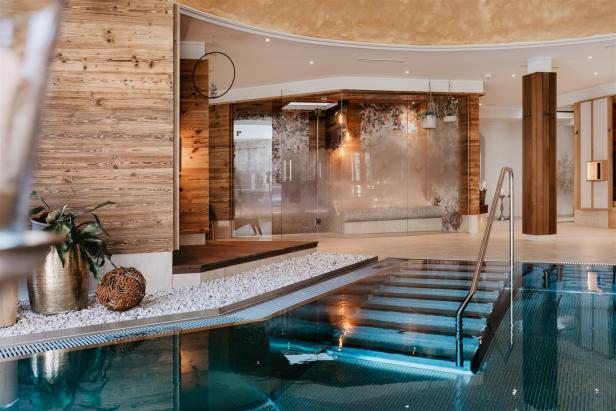 Ein Innenpool mit Treppe und dekorativen Elementen in einem Wellnessbereich.