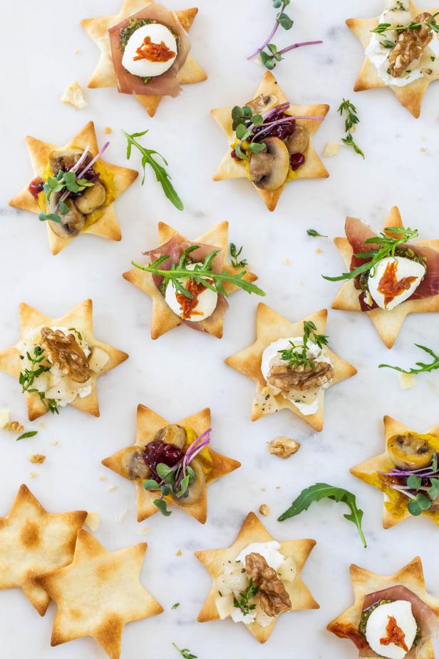 Sternförmige Cracker mit Käse, Fleisch und Kräutern, appetitlich angerichtet auf einem eleganten Teller.