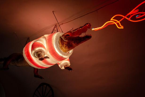 Ein Krokodil hängt von der Decke und „spuckt“ rote Neonröhren.