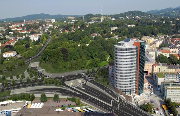 Luftaufnahme einer Stadtlandschaft mit einem modernen Bürogebäude und einer Autobahn mit Tunneln.