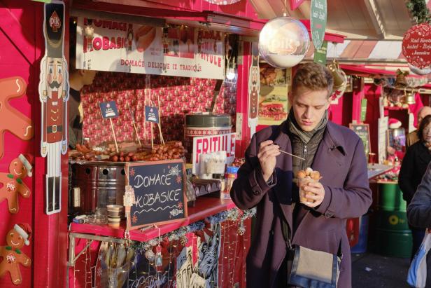 Ein Mann isst „Fritule“ auf einem Christkindlmarkt in Zagreb.