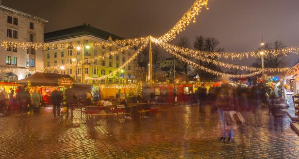 Ein belebter Weihnachtsmarkt mit funkelnden Lichtern in Helsinki bei Nacht.