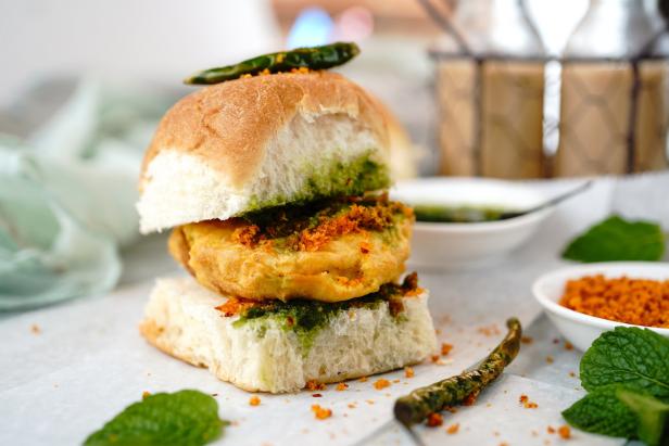 Ein Vada Pav, ein indischer vegetarischer Streetfood-Burger, mit grünen Chilis und Minze garniert.
