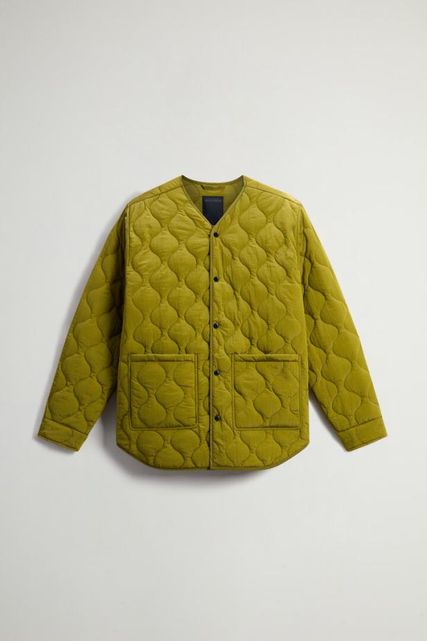 Eine gesteppte, olivgrüne Jacke mit Knöpfen und zwei Taschen.