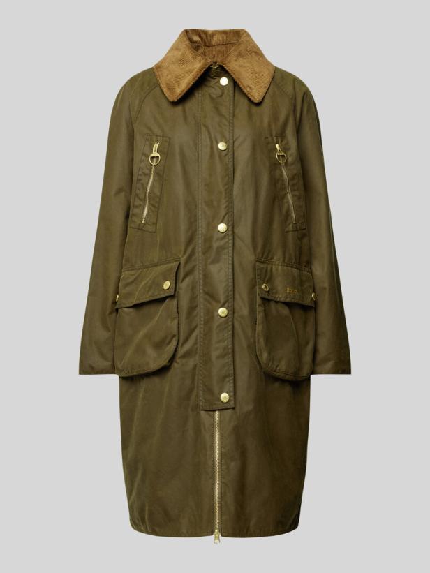 Eine lange, olivgrüne Wachsjacke mit goldenen Knöpfen und einem Kragen aus braunem Cord.