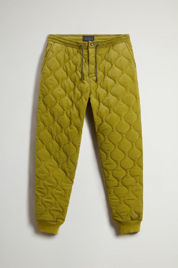 Eine gesteppte, olivgrüne Hose mit Kordelzug liegt vor einem weißen Hintergrund.