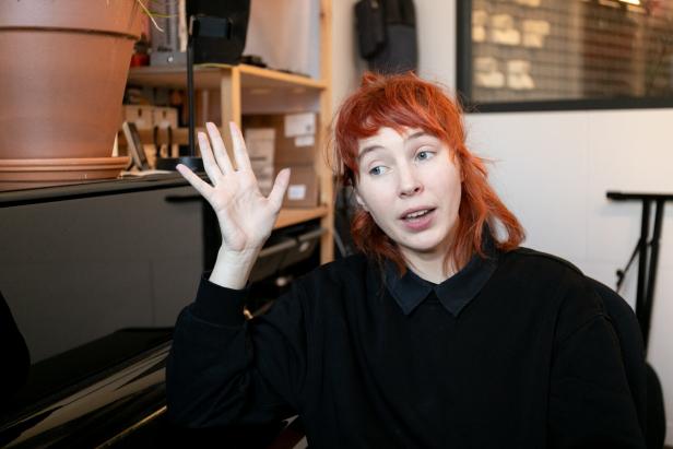 Mira Lu Kovacs gestikuliert neben einem Klavier.