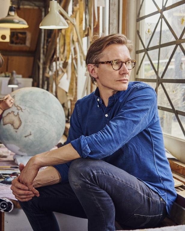 Peter Bellerby sitzt in seiner Werkstatt vor einem Globus.