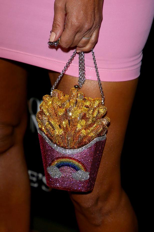 Kim Kardashian hält eine mit Strass besetzte Handtasche in Form einer Pommestüte.