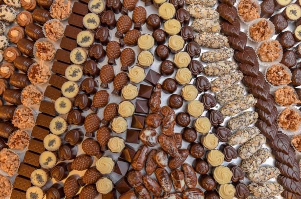 Verschiedene Pralinen und Schokoladenstücke liegen auf einer Fläche.
