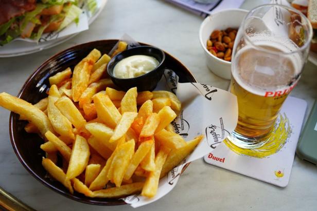 Ein Teller Pommes Frites mit Mayonnaise und ein Glas Bier auf einem Tisch.
